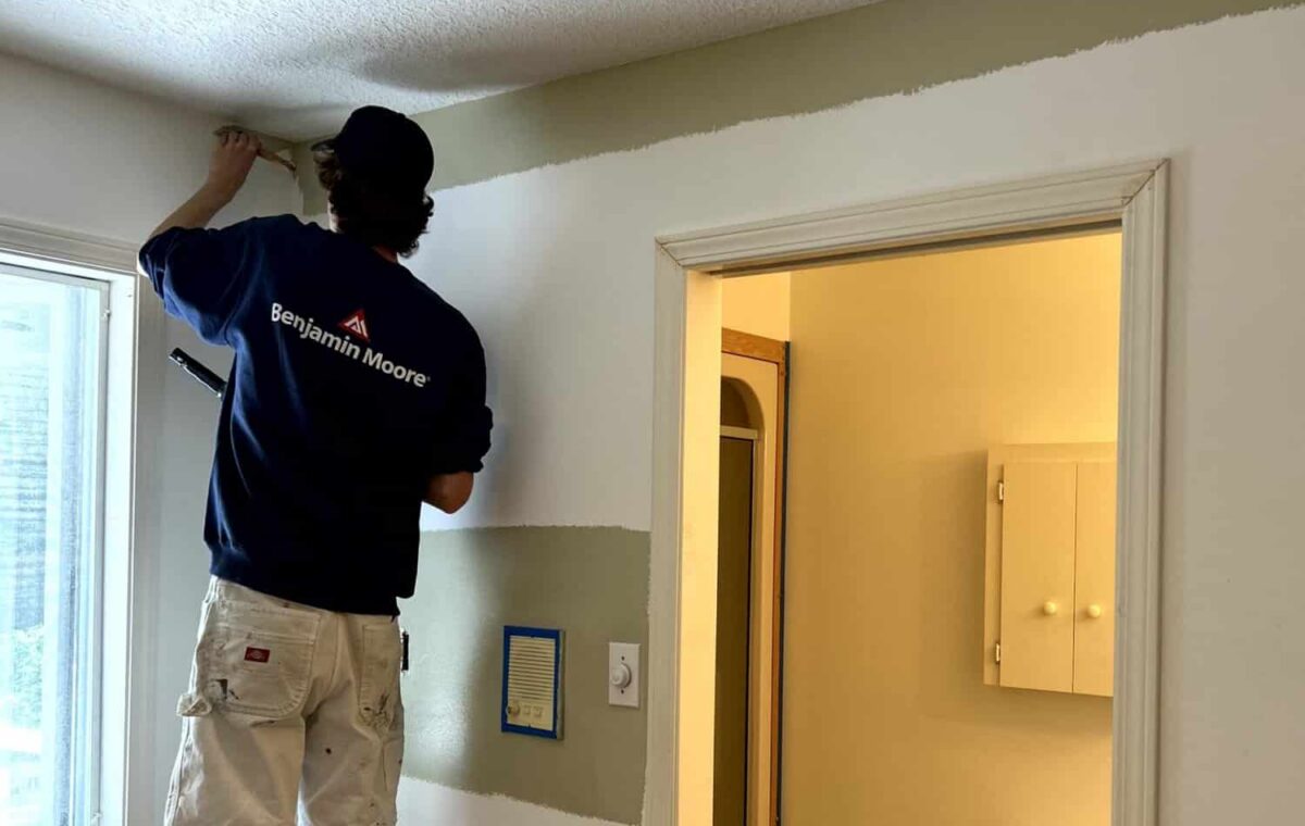 a-man-on-a-ladder-painting-white-on-the-wall.jpg ways to protect furniture - a man on a ladder painting white on the wall