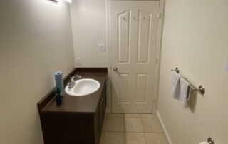 Cream-painted bathroom with white trim, dark wood vanity, white porcelain sink, and tile flooring in Parksville, BC