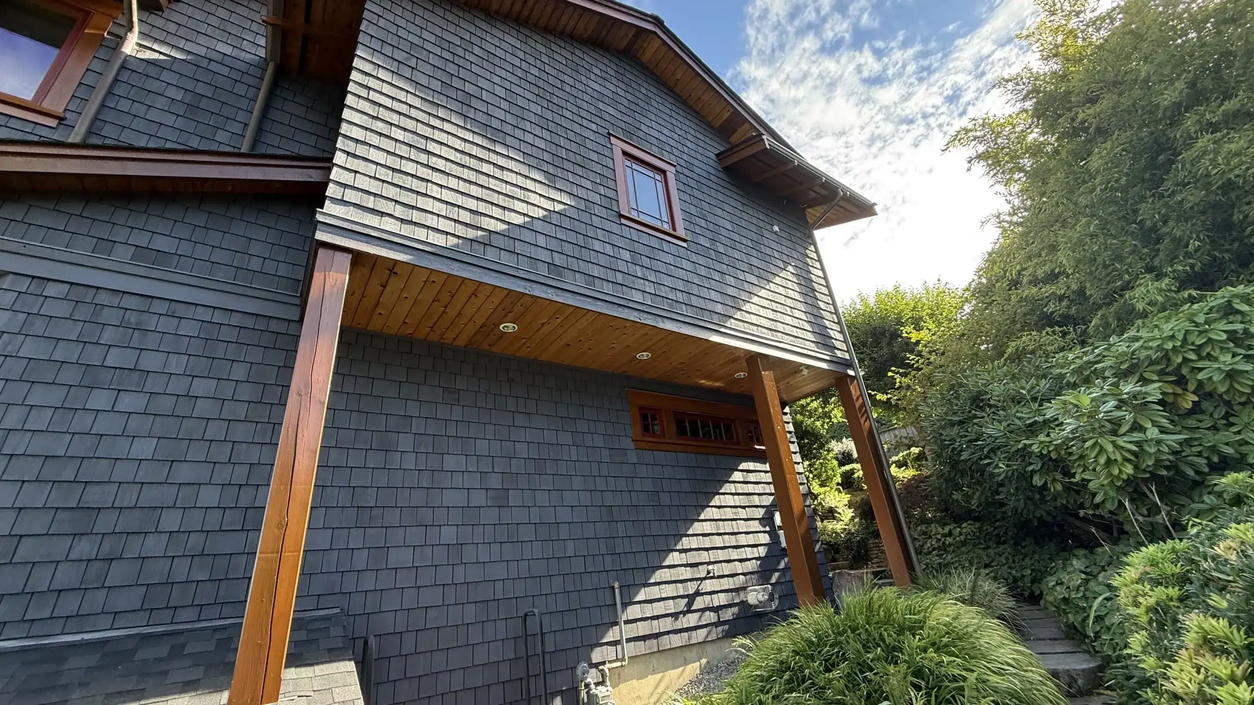 Blue-Gray Shingle Siding Exterior Blue-gray shingle siding residential home with warm wood trim, covered entry, and cedar shake roofing in Parksville, BC