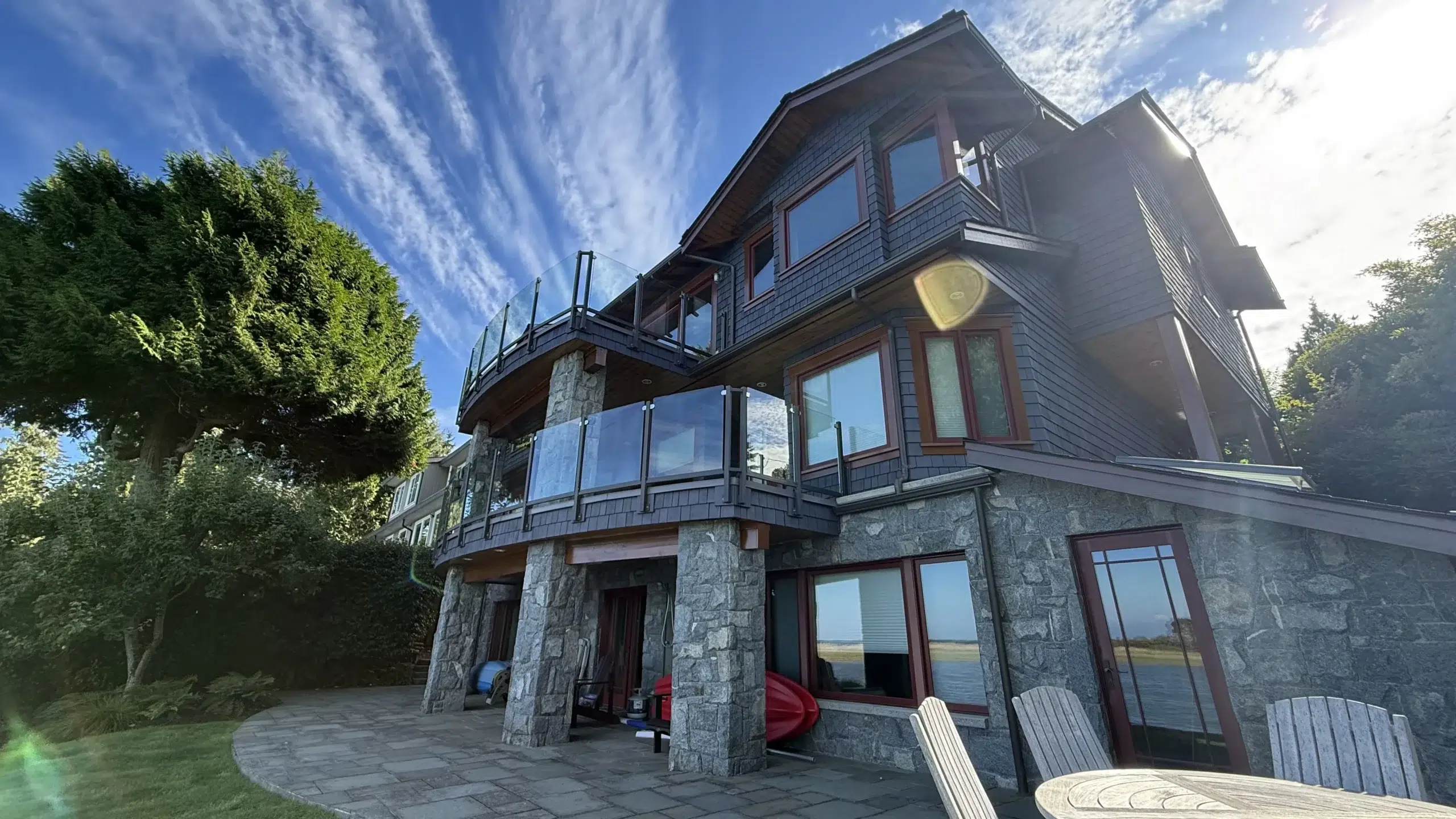 Modern Charcoal Home with Stone Base Modern charcoal-painted residential home with stone foundation, black-framed windows, and multi-level deck in Parksville, BC