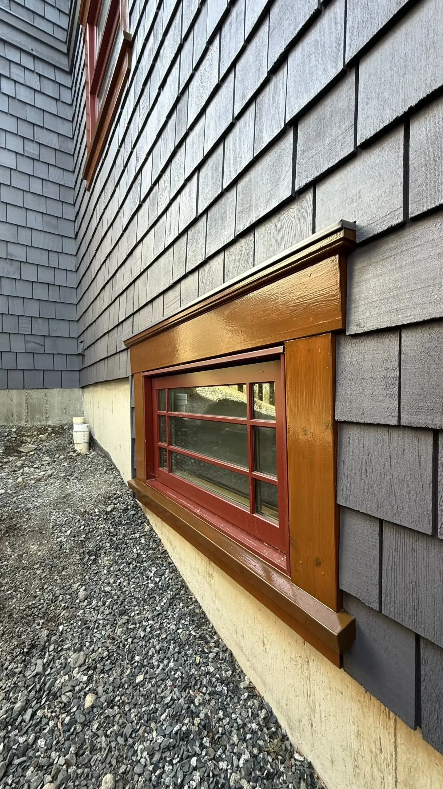 Gray Hardie Board Residential Exterior Gray textured hardie board siding with red-trim window and golden-stain wood trim on residential home in Parksville, BC
